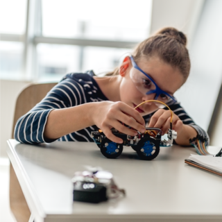 Schülerin tüftelt an einem selbstgebauten Modell.