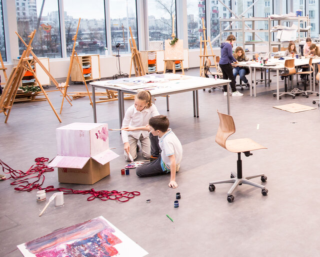 Zwei Kinder bemalen einen Karton in einem Kunstraum
