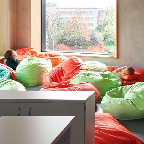 Helle Raumecke mit bunten Sitzsäcken und zwei Kindern | © ganztag-klein