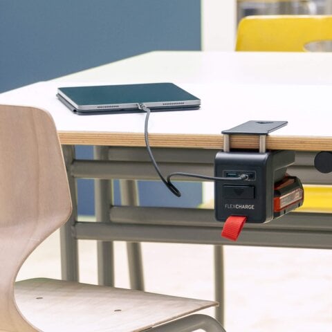 Schultisch mit einem angeklemmten FLEXCHARGE Akkuladegerät, das ein iPad auflädt