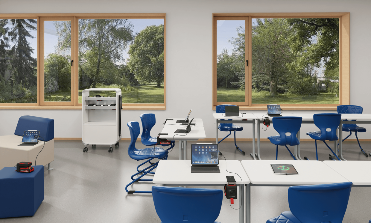 Klassenraum mit einem FLEXCHARGE Caddy und Akkuladegeräten an Tischen und Sofas.