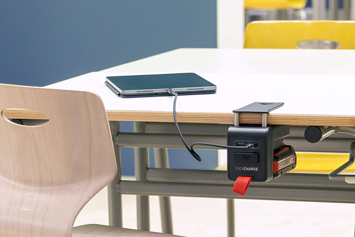 Schultisch mit einem angeklemmten FLEXCHARGE Akkuladegerät, das ein iPad auflädt